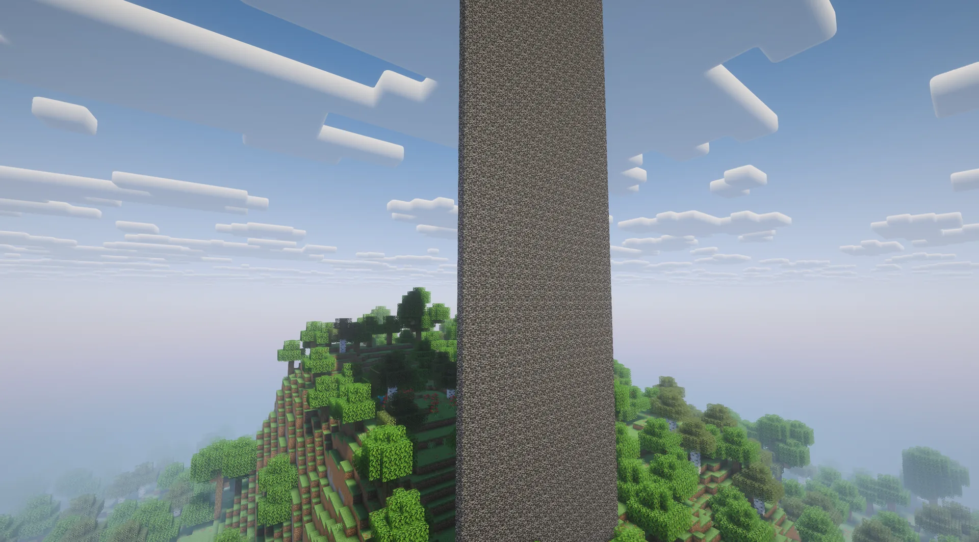 Tall bedrock column rises above a forested hill; no player is visible.
