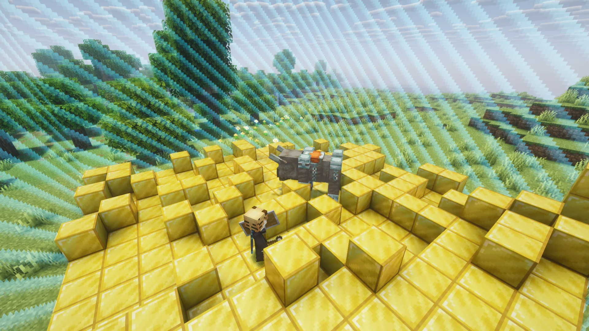 A player holding an axe and shield stands on gold blocks facing a ravager inside a blue chunk border.